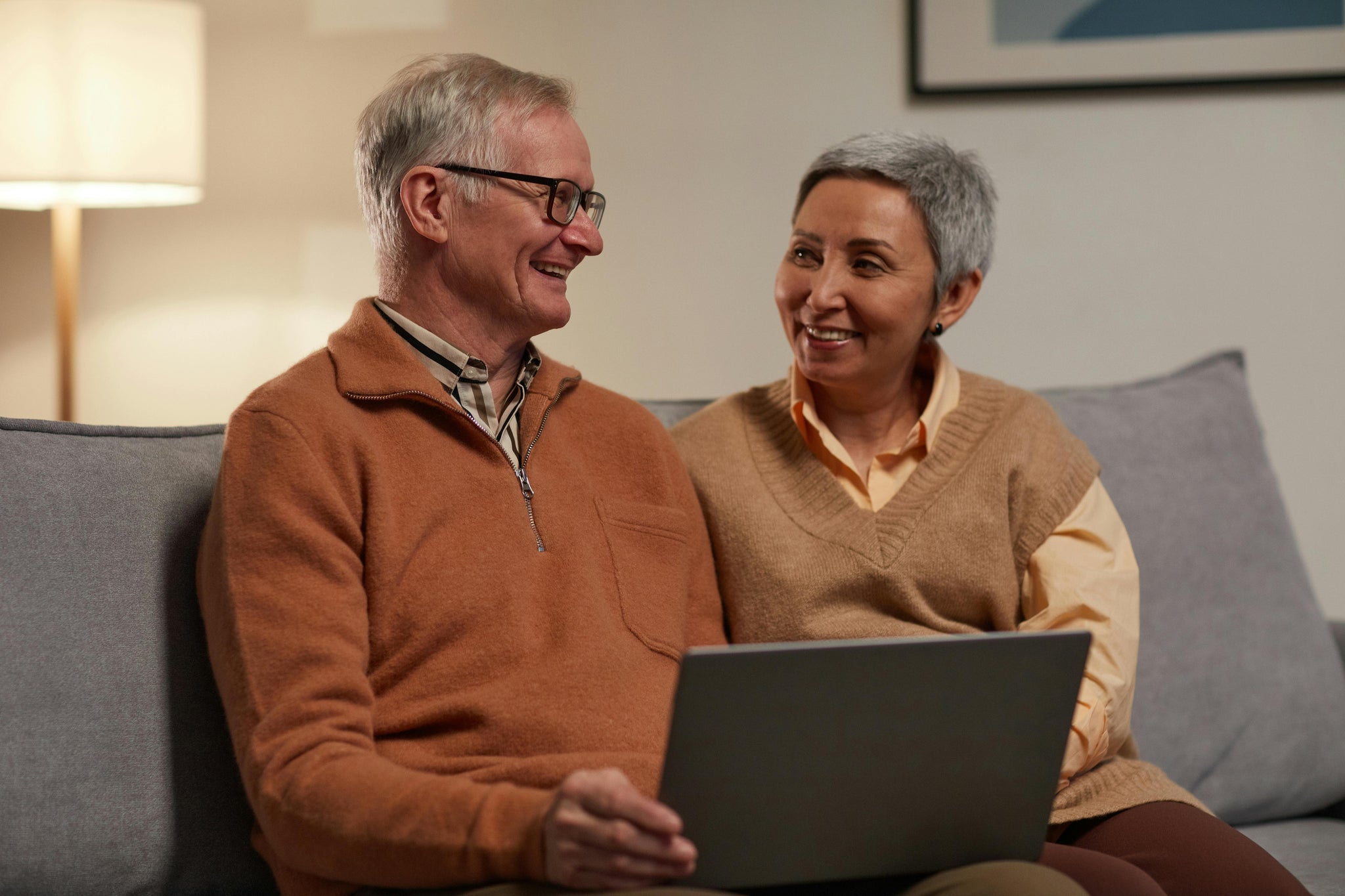 A couple is playing with a tablet on the couch